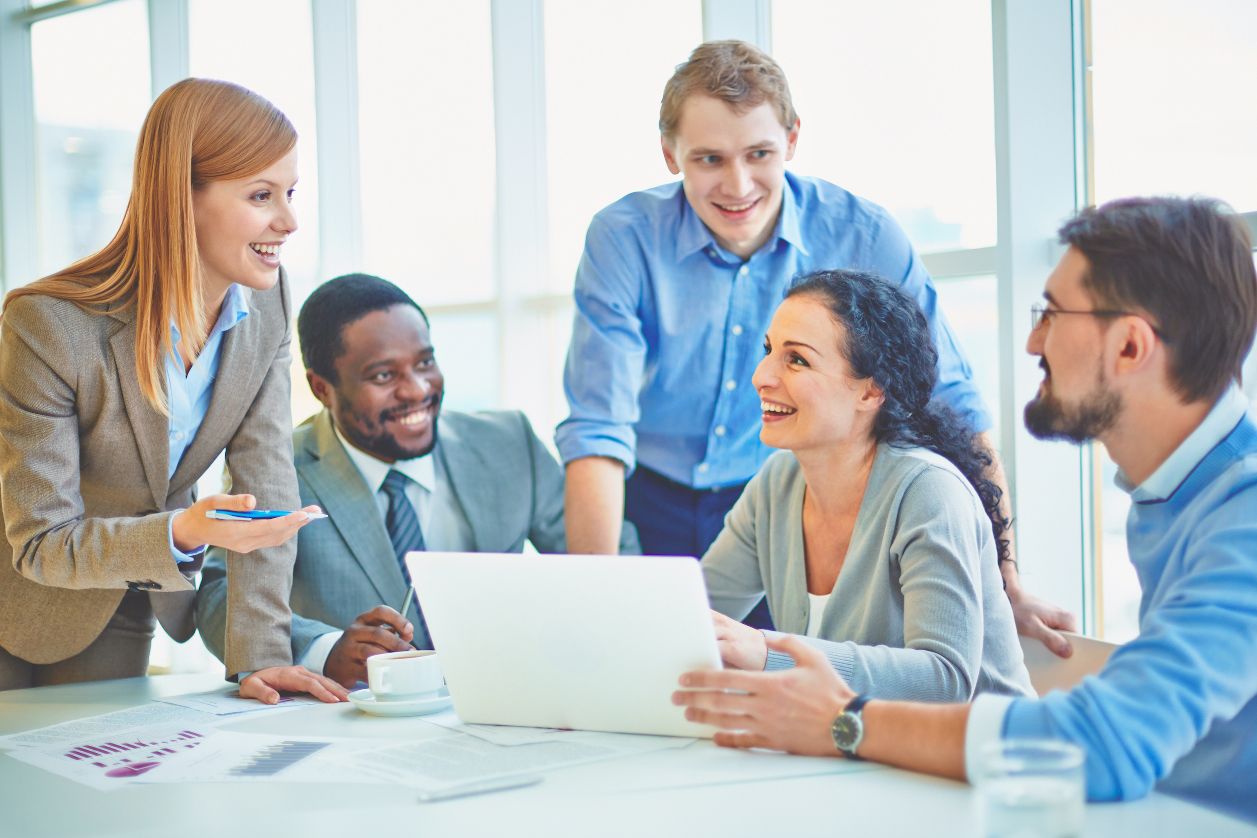 People in office happily discussing around a laptop